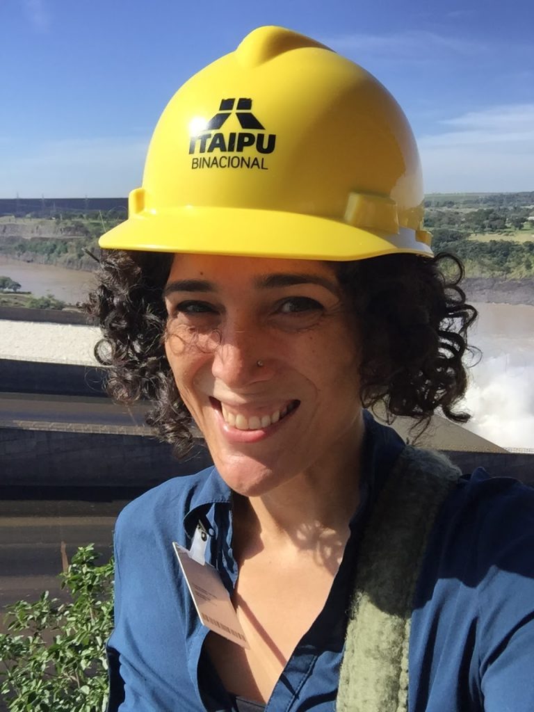 Christine Folch wearing a hard hat in front of a dam