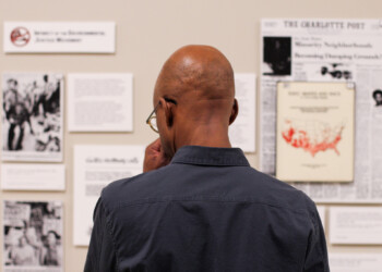 A man stands in front of the exhibit wall, looking pensive.